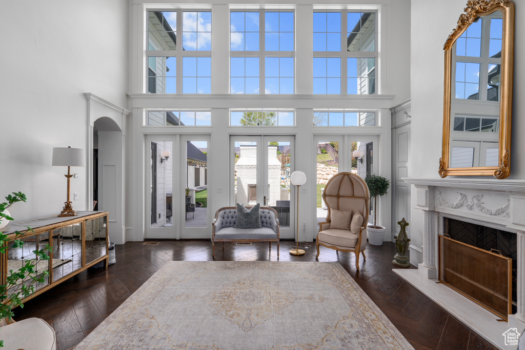 Living room featuring dark parquet flooring, french doors, a high ceiling, and a fireplace