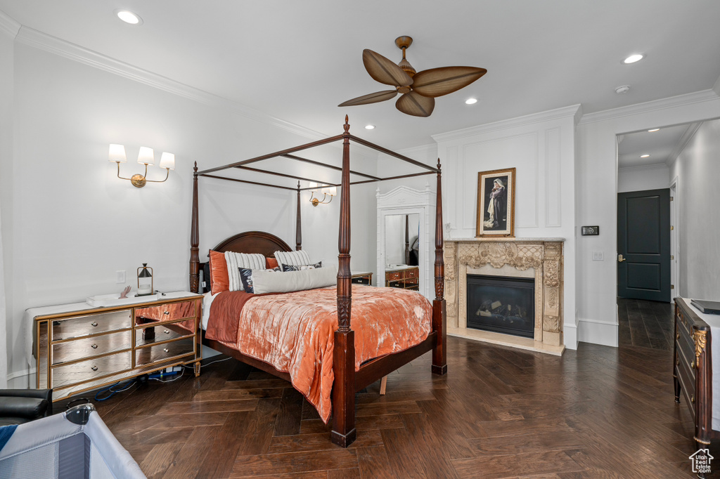 Bedroom with dark parquet floors, ceiling fan, crown molding, and a premium fireplace