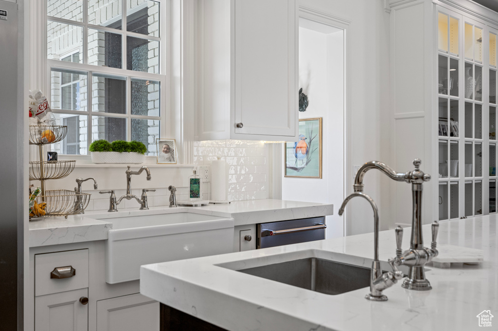 Kitchen featuring backsplash, white cabinetry, and light stone countertops