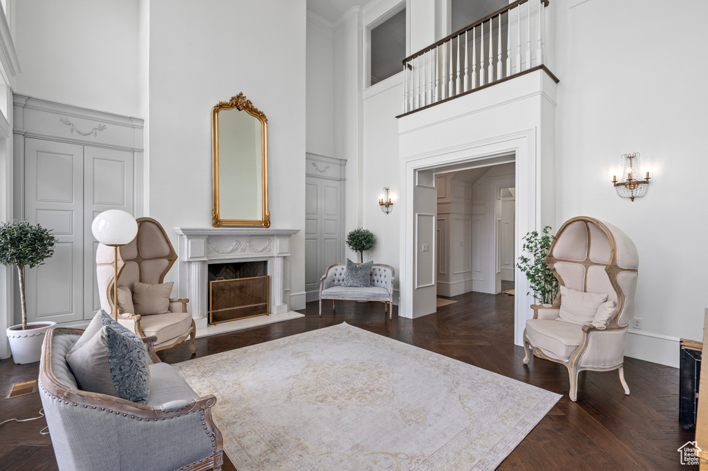 Living room with a fireplace, dark parquet flooring, and a high ceiling