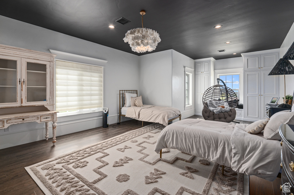 Bedroom with an inviting chandelier and dark hardwood / wood-style flooring