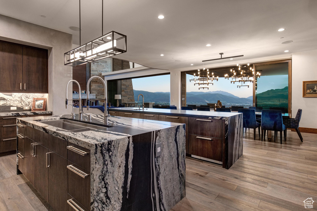 Kitchen with an island with sink, light wood-type flooring, a mountain view, and pendant lighting