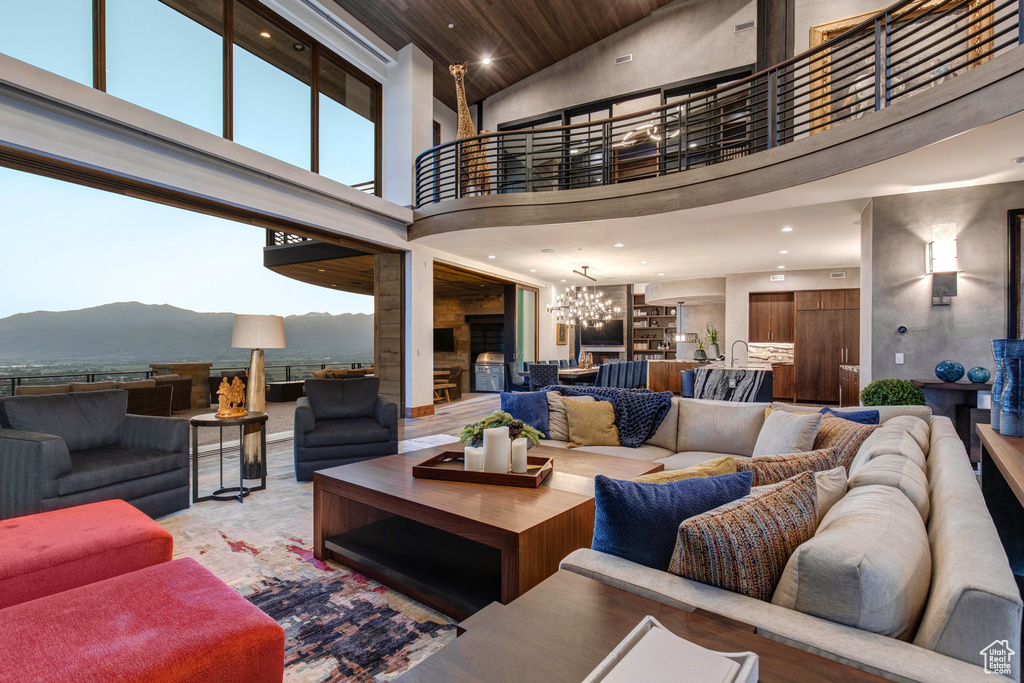 Living room with high vaulted ceiling, an inviting chandelier, a mountain view, and wooden ceiling