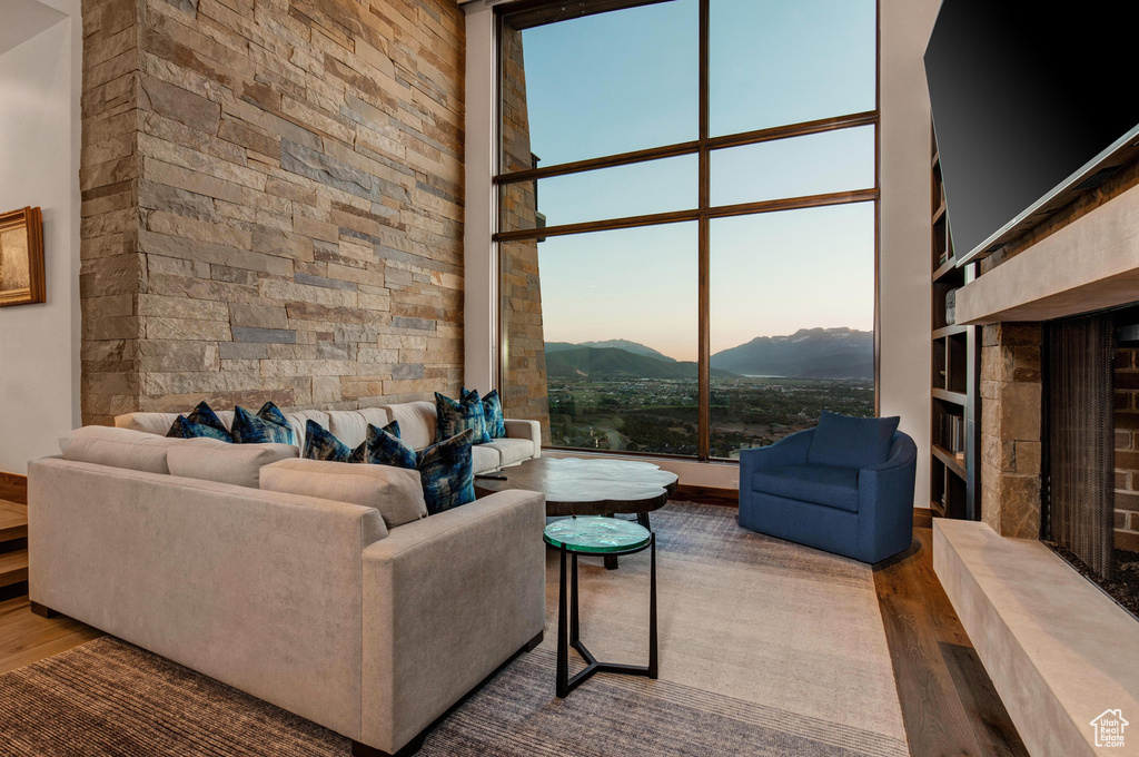 Living room featuring a fireplace, a mountain view, hardwood / wood-style flooring, a high ceiling, and floor to ceiling windows