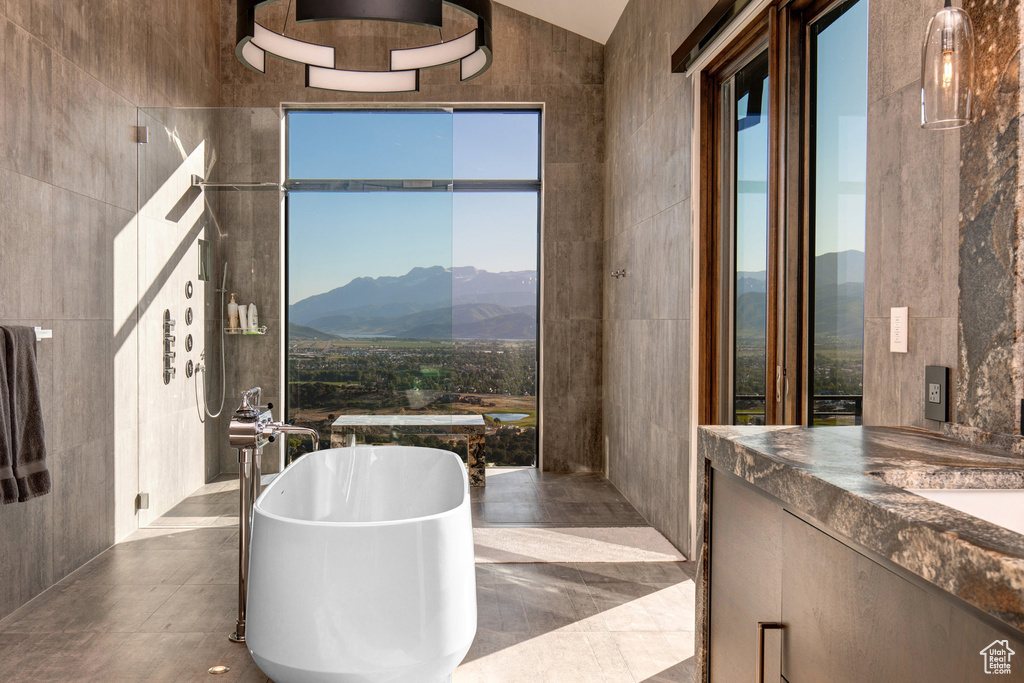 Bathroom with tile walls, a bathtub, tile flooring, and a mountain view