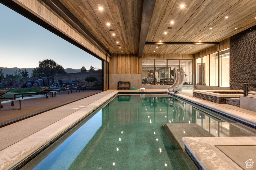 Pool at dusk with a water slide and a patio area