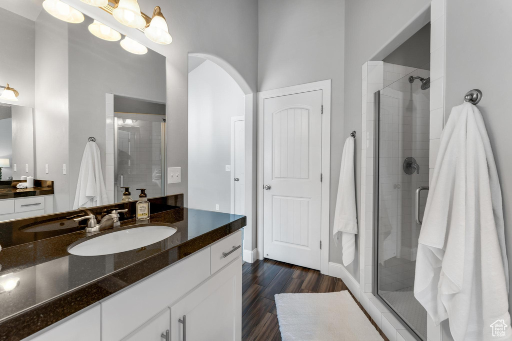 Bathroom with vanity, hardwood / wood-style flooring, and a shower with shower door