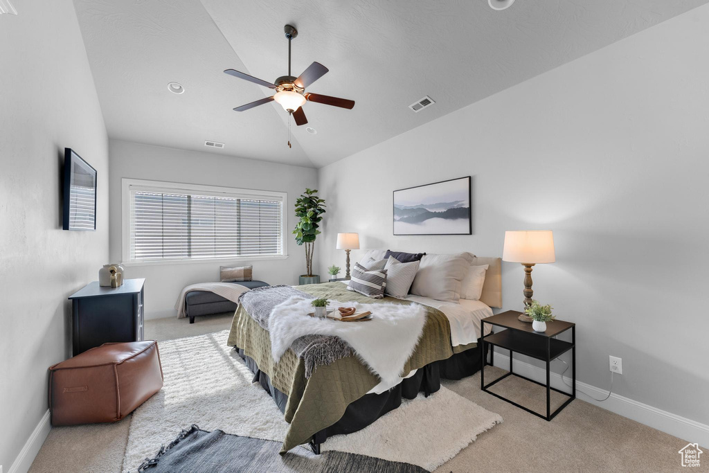 Bedroom with light carpet, ceiling fan, and vaulted ceiling