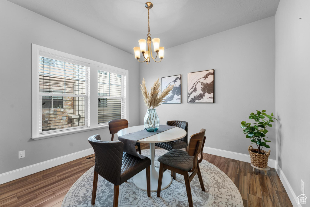 Dining room with dark hardwood / wood-style floors and an inviting chandelier