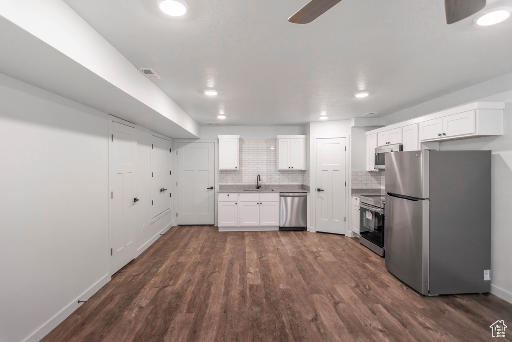 Kitchen featuring backsplash, stainless steel appliances, dark hardwood / wood-style flooring, and white cabinetry