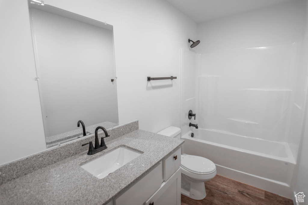 Full bathroom with shower / tub combination, hardwood / wood-style floors, toilet, and vanity