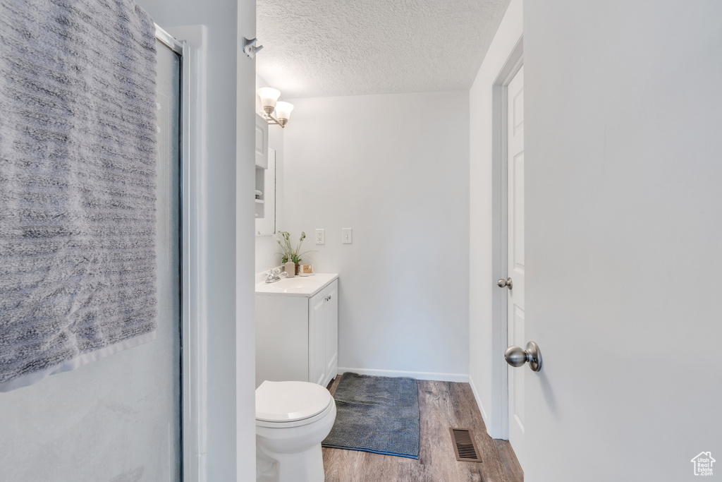 Bathroom with a textured ceiling, toilet, vanity, and hardwood / wood-style floors