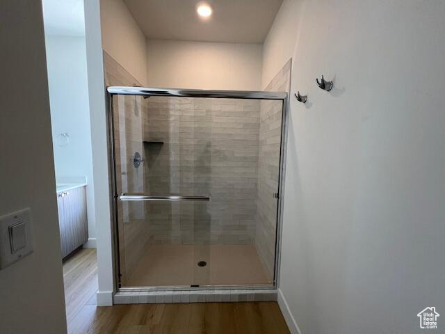 Bathroom featuring hardwood / wood-style flooring and a shower with shower door