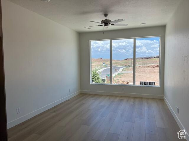 Spare room featuring a wealth of natural light, hardwood / wood-style flooring, and ceiling fan