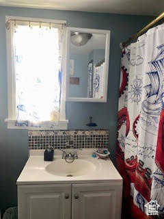 Bathroom featuring vanity with extensive cabinet space and tasteful backsplash