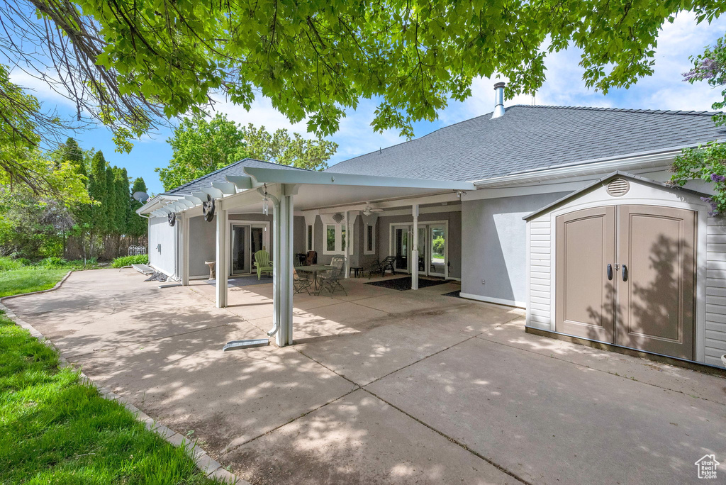 Rear view of house with a storage unit and a patio area