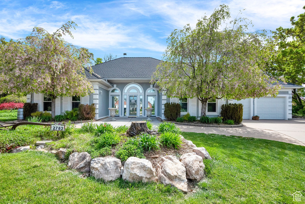 View of front of home featuring french doors, a front lawn, and a garage