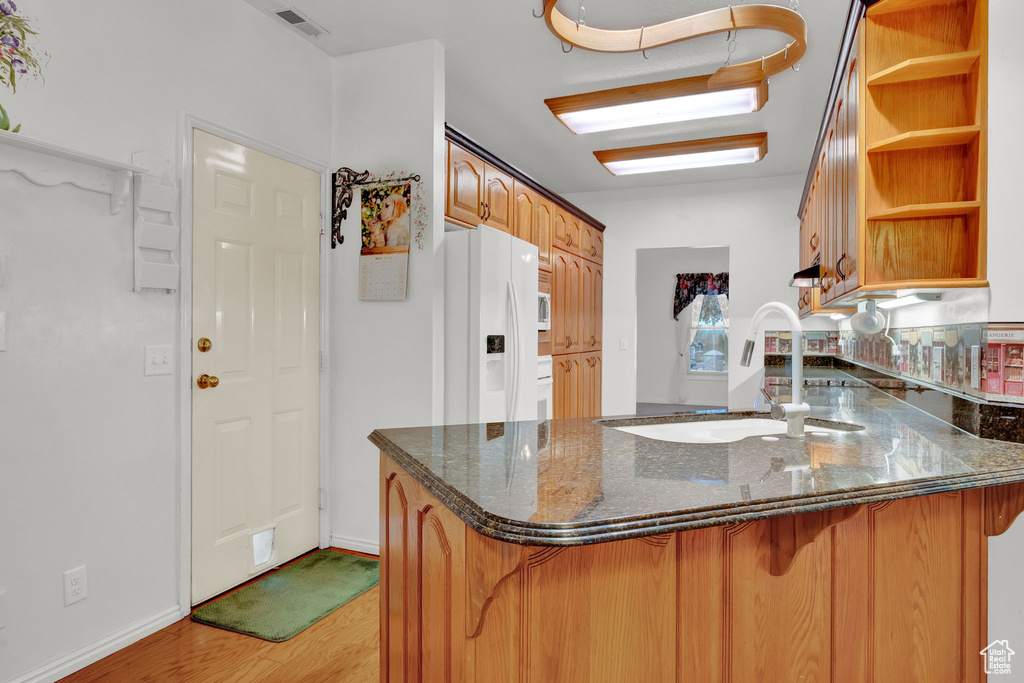 Kitchen with light hardwood / wood-style flooring, sink, kitchen peninsula, and white refrigerator with ice dispenser