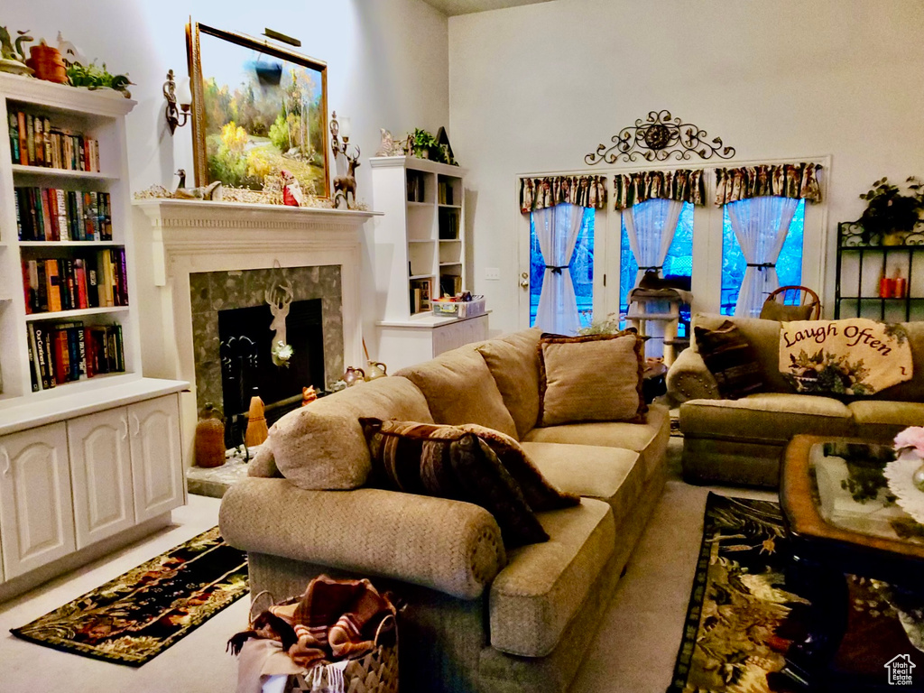 Living room featuring carpet flooring, a fireplace, and built in shelves