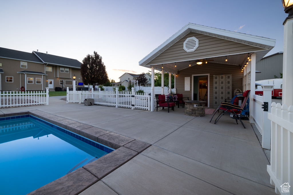 View of swimming pool featuring a patio area, a fenced backyard, and a fire pit