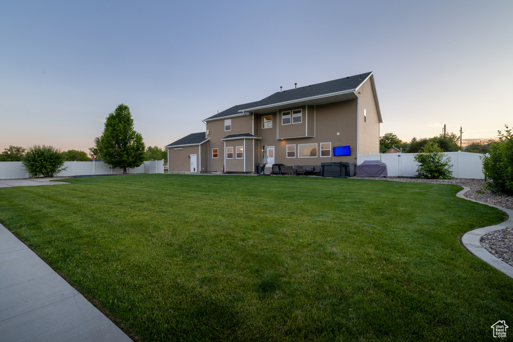 Back of house at dusk with a fenced backyard
