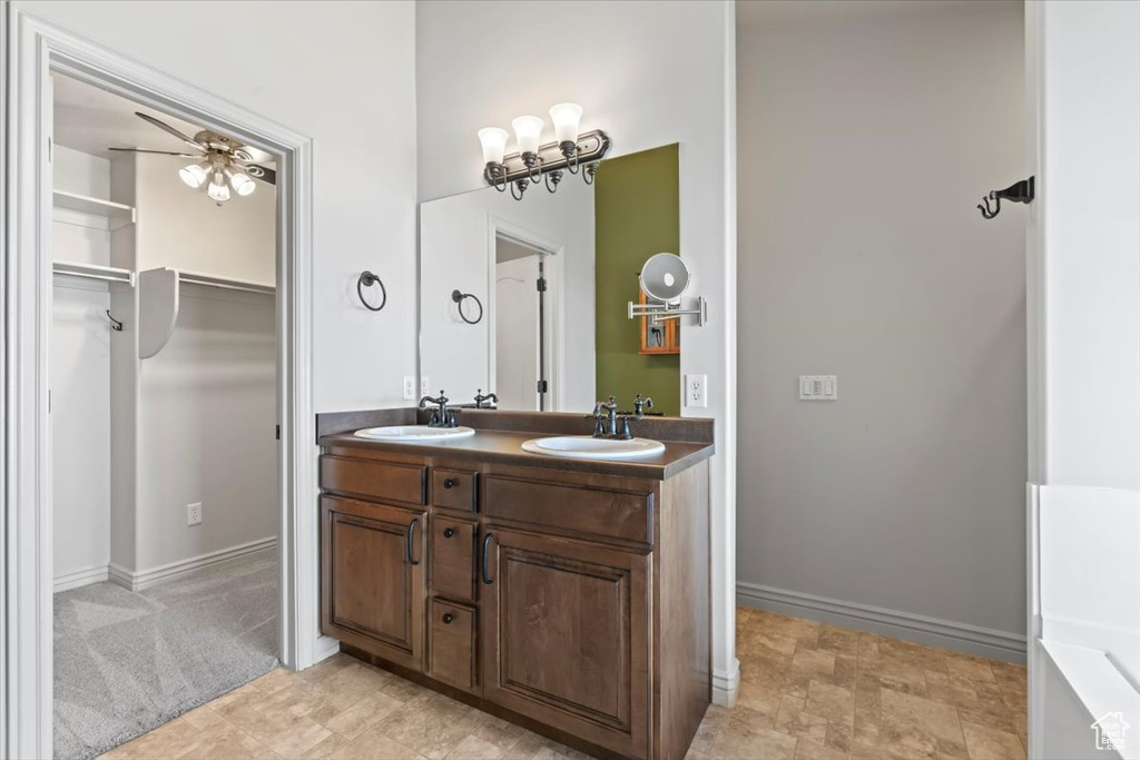 Bathroom featuring double sink vanity, ceiling fan, and tile floors