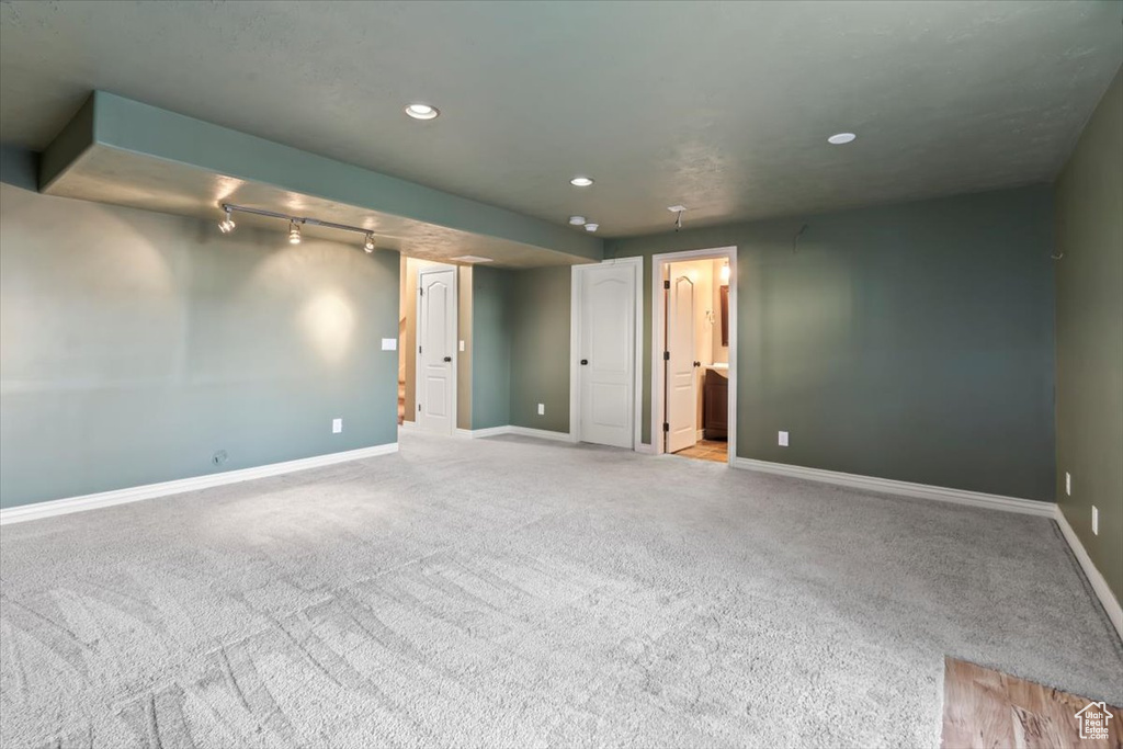Empty room featuring track lighting and light colored carpet