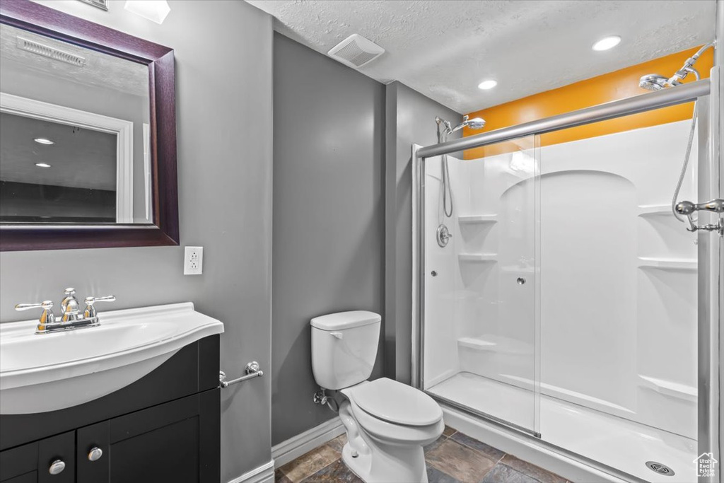 Bathroom featuring toilet, tile floors, an enclosed shower, vanity, and a textured ceiling