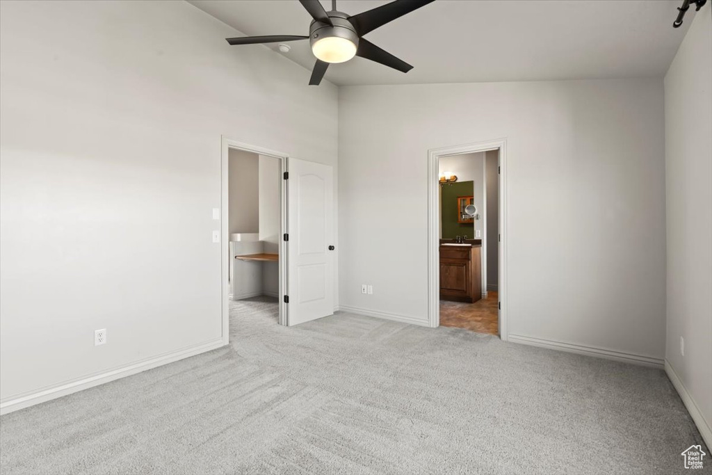 Unfurnished bedroom with light carpet, high vaulted ceiling, connected bathroom, and ceiling fan