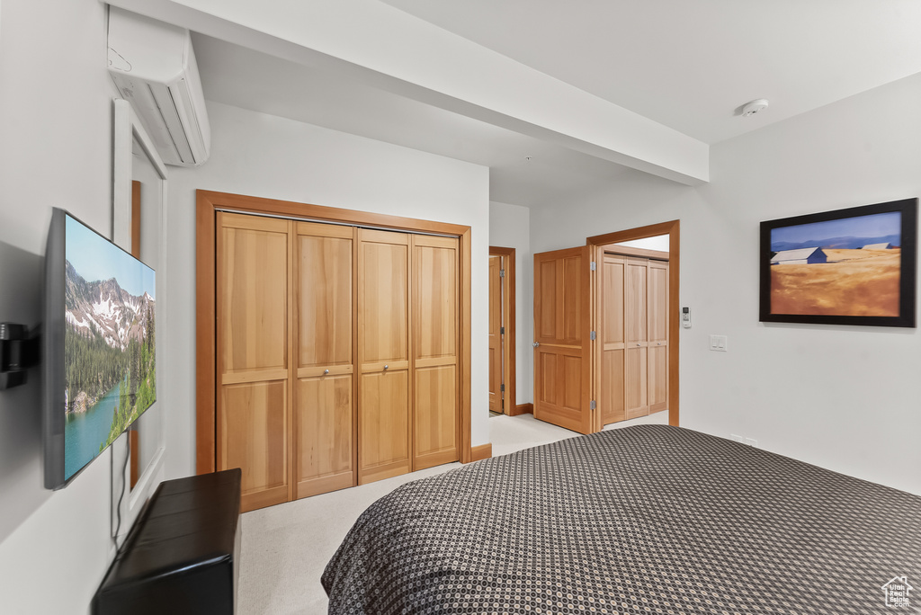 Bedroom featuring a closet, carpet floors, and a wall mounted air conditioner