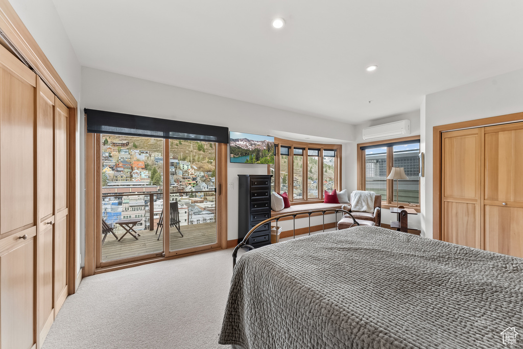 Carpeted bedroom featuring a wall mounted air conditioner, a closet, and access to outside