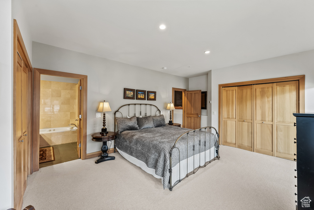 Carpeted bedroom featuring ensuite bathroom and a closet