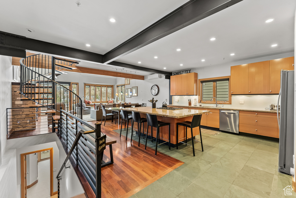 Kitchen featuring light stone countertops, beamed ceiling, light tile floors, a breakfast bar, and appliances with stainless steel finishes