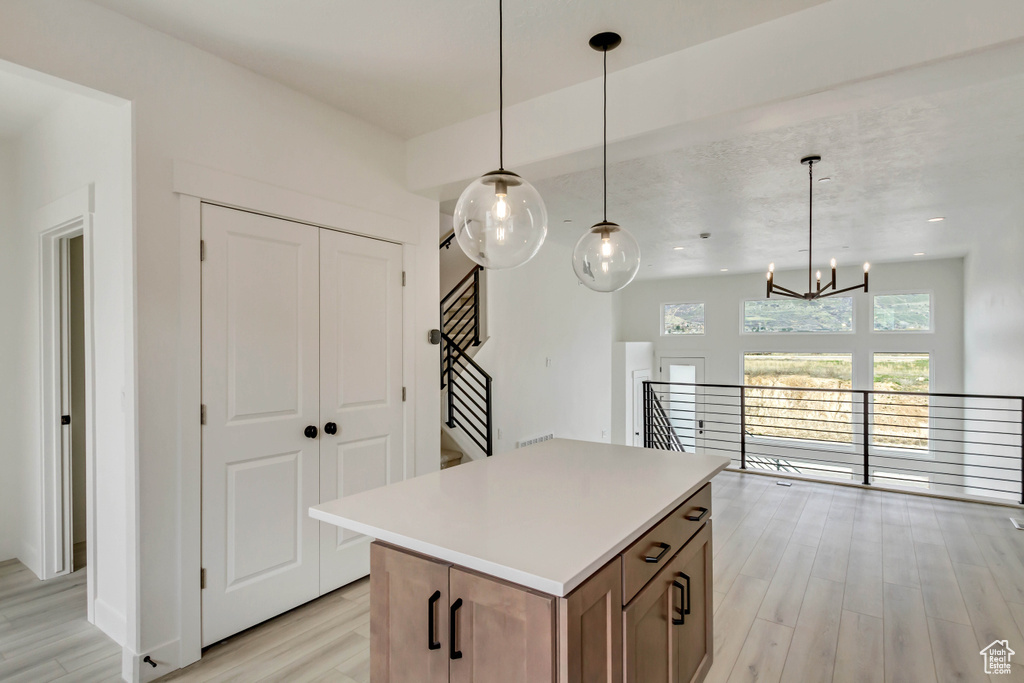 Kitchen featuring a kitchen island, a chandelier, hanging light fixtures, and light wood-type flooring