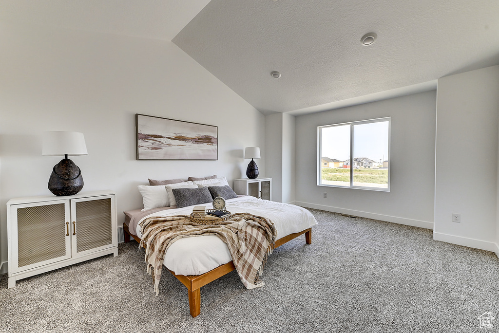 Bedroom featuring light carpet and vaulted ceiling