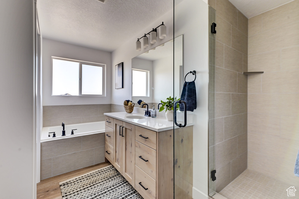 Bathroom featuring vanity, a textured ceiling, wood-type flooring, and independent shower and bath