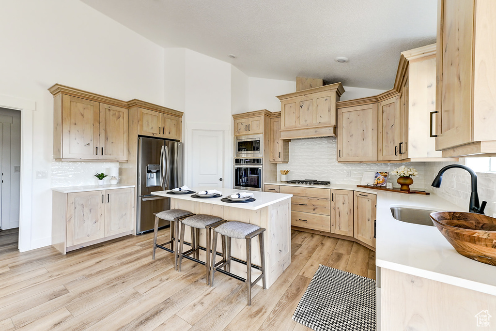 Kitchen featuring stainless steel appliances, sink, a center island, and light brown cabinets