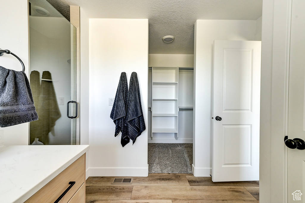 Bathroom featuring wood-type flooring, an enclosed shower, a textured ceiling, and vanity