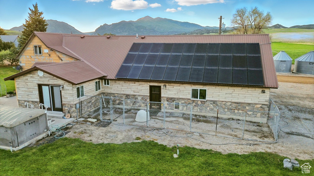 Back of property with stone siding, solar panels, a mountain view, and metal roof