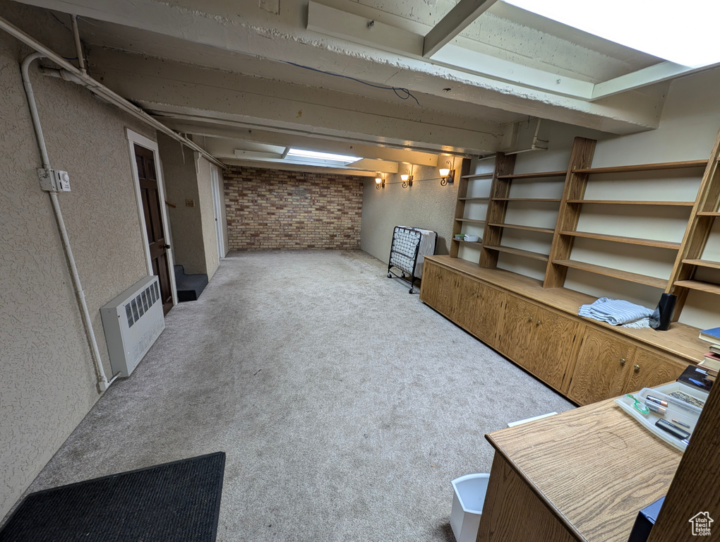 Basement featuring carpet flooring and brick wall