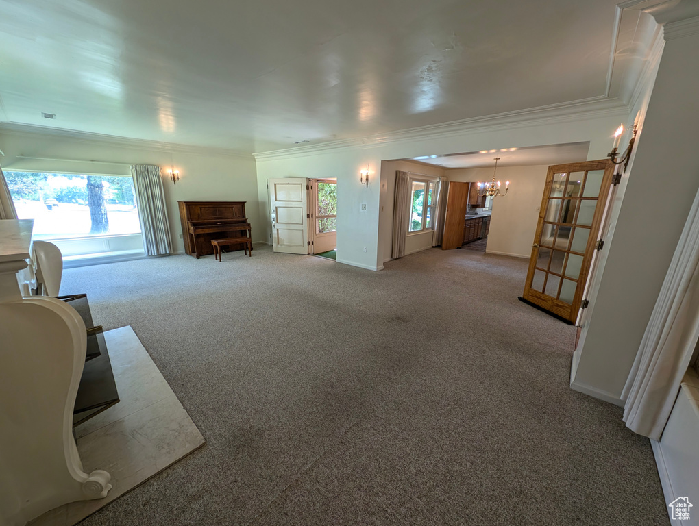 Living room featuring crown molding, an inviting chandelier, light colored carpet, and french doors