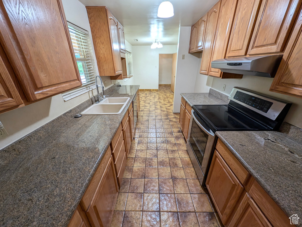 Kitchen featuring tile patterned flooring, stainless steel electric range, and sink