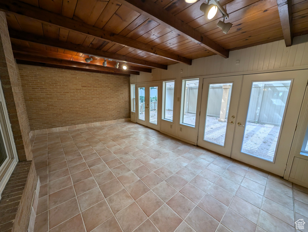 Interior space with brick wall, wooden ceiling, light tile patterned floors, and track lighting