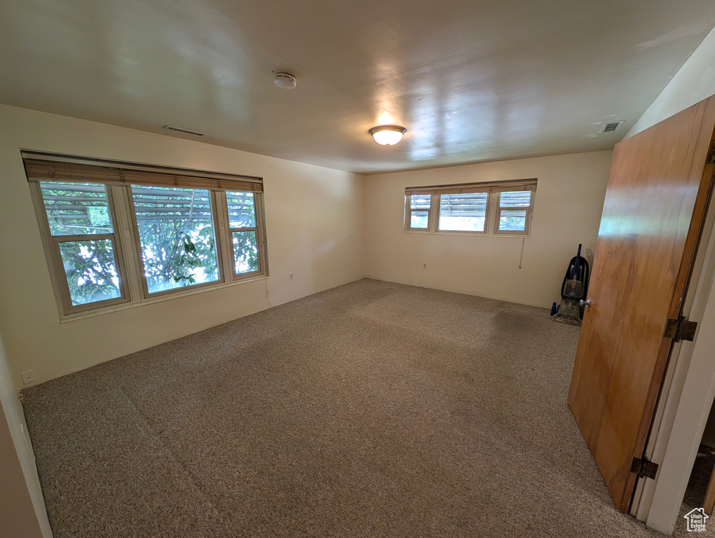 Unfurnished room featuring carpet and plenty of natural light