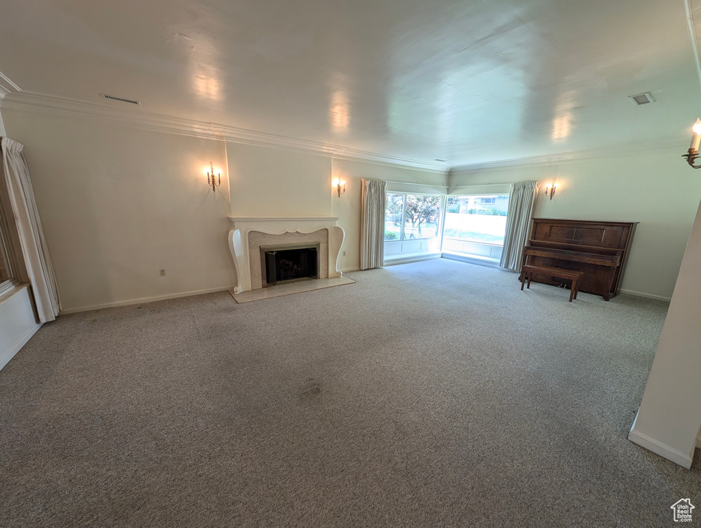 Unfurnished living room featuring light carpet, a fireplace, and crown molding