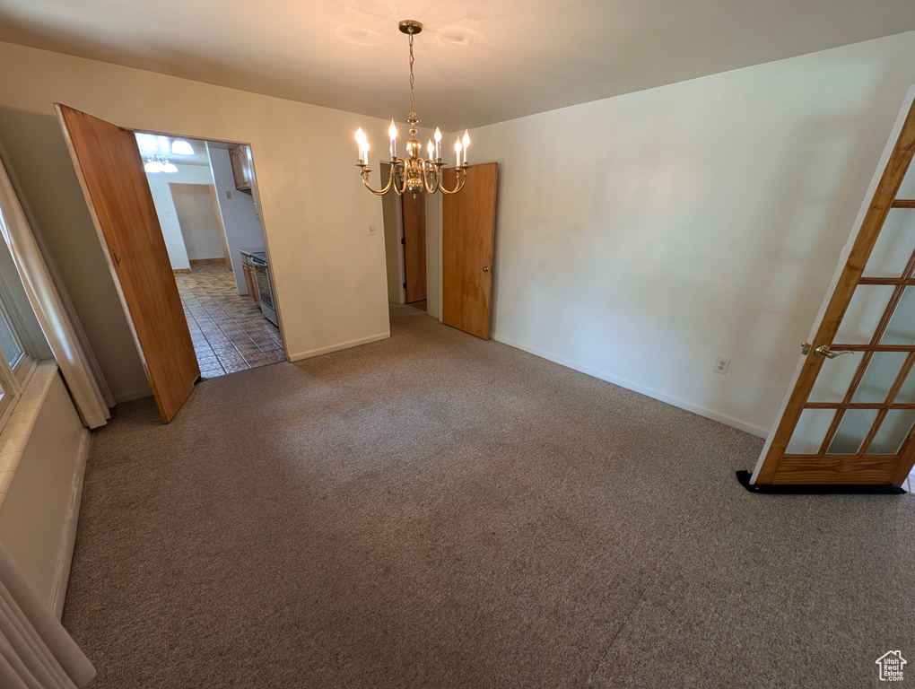 Carpeted spare room with a notable chandelier