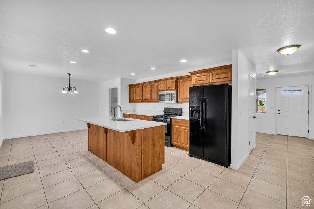 Kitchen featuring an island with sink, black appliances, sink, and light tile floors