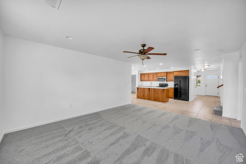 Unfurnished living room featuring sink, light tile flooring, and ceiling fan