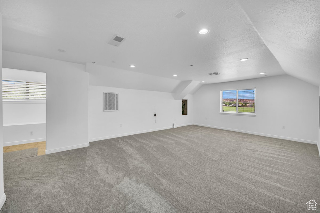 Bonus room with carpet, a textured ceiling, and lofted ceiling