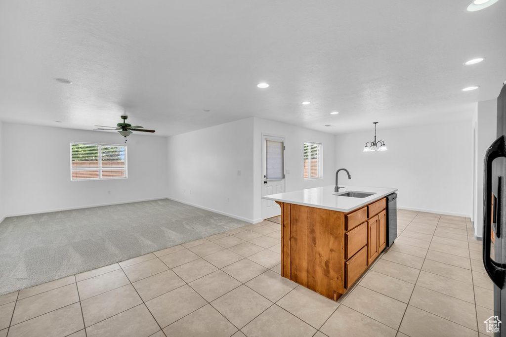 Kitchen featuring decorative light fixtures, sink, light tile floors, and a kitchen island with sink